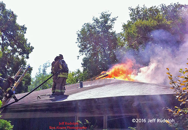 firefighters on house roof with flames