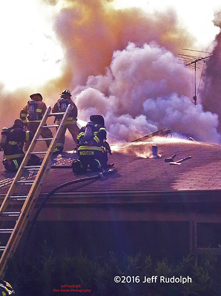 firefighters on house roof with heavy smoke