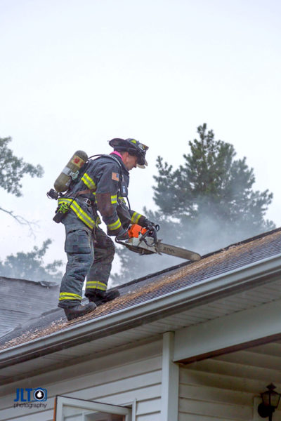 firefighter ventilates roof during fire
