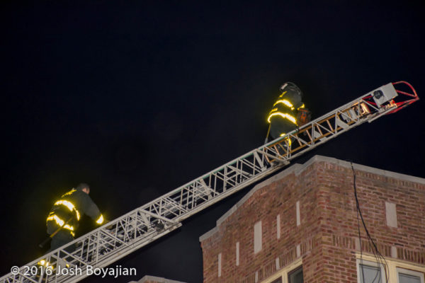 firefighters climb aerial ladder at night