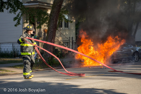 firefighter attacks a car fully engulfed in fire