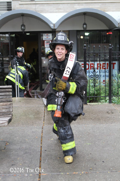 female firefighter pulls hose after a fire
