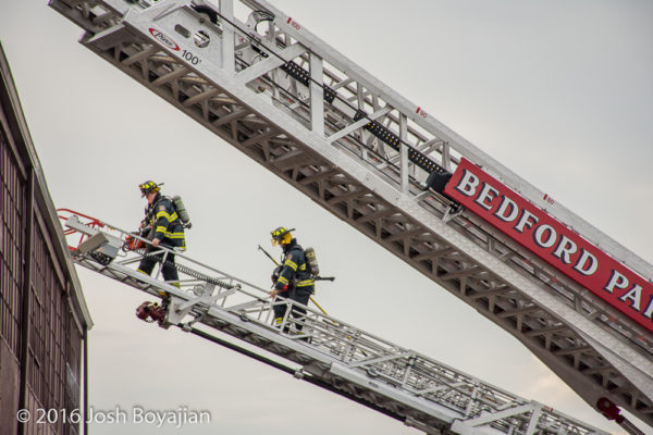 firefighters climb aerial ladder at fire scene