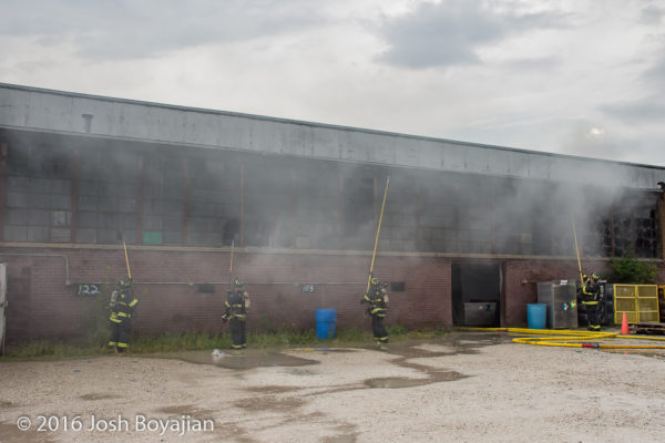 firemen break windows at warehouse with pike poles