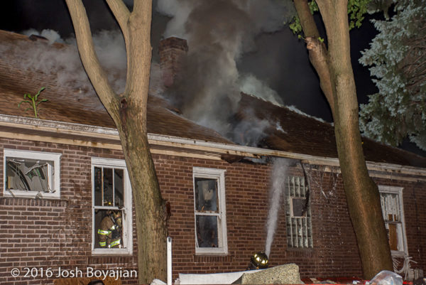 heavy smoke through roof of a house on fire