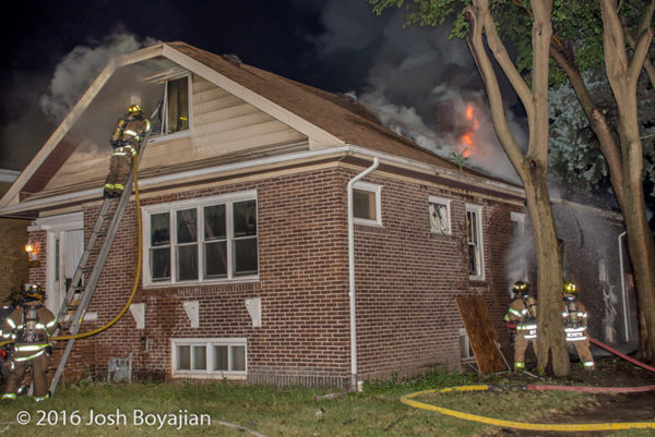 firefighters battle fire through the roof of a house on fire