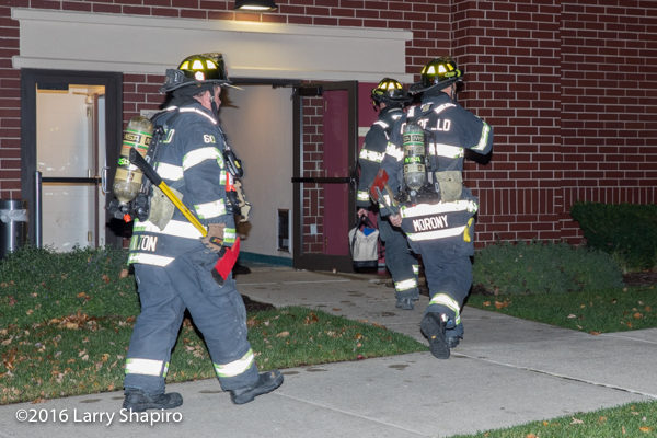 Firefighters enter building with tools and PPE