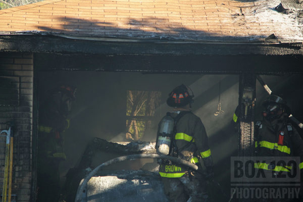 firefighters wash down the aftermath of attached garage fire