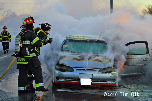Firefighters extinguish a car on fire on the highway