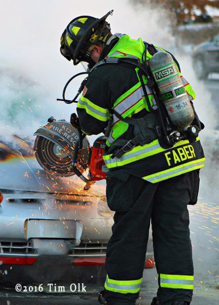 Firefighter uses saw on car hood