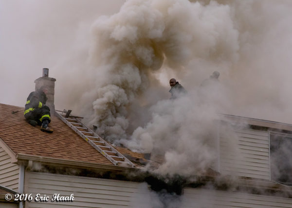 Firefighters engulfed in smoke on house roof