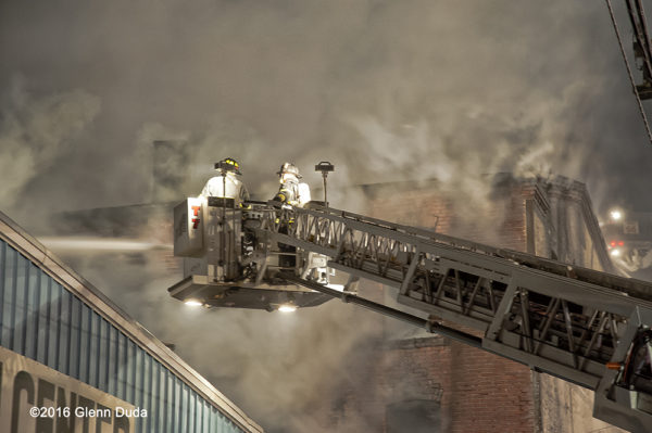 Firefighters in tower ladder bucket battle warehouse fire