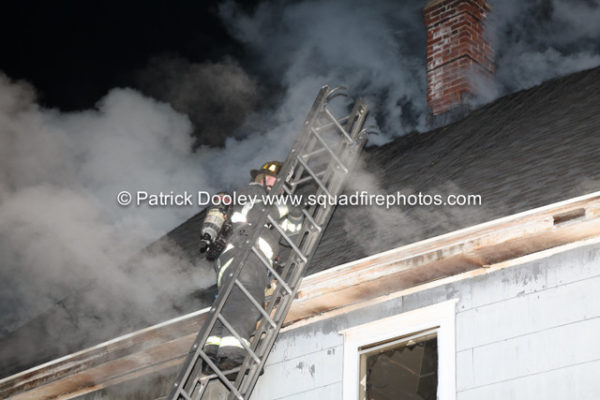 firefighter on ladder carrying a roof ladder