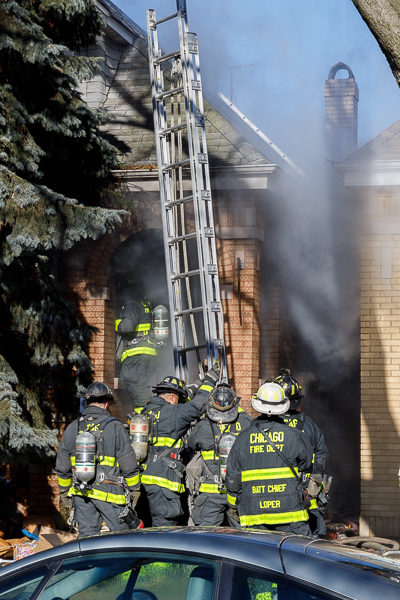 firefighters position ground ladder during fire