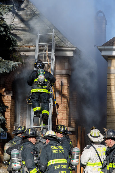 firefighter climbs ground ladder during fire