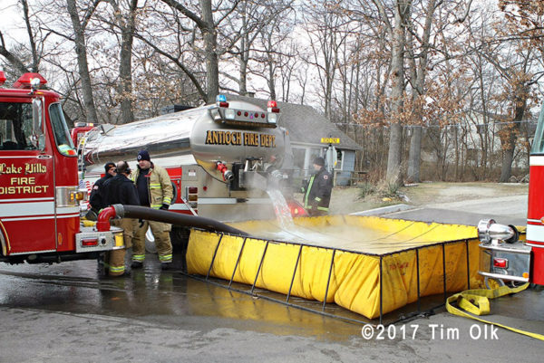 fire department water tanker dumping into portable tank
