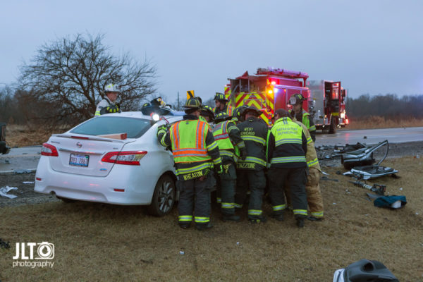 firefighters work to free occupants trapped in a car