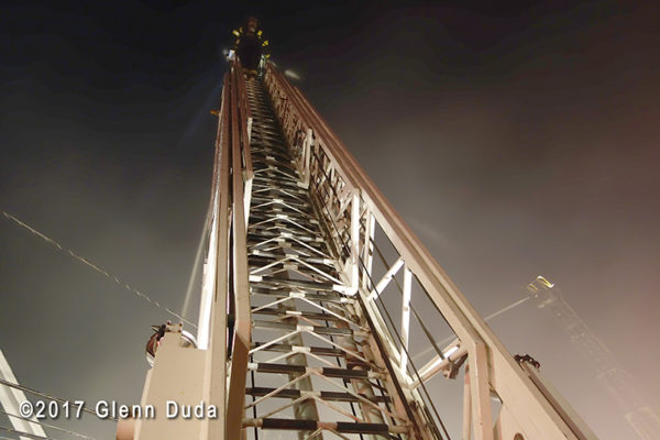 looking up a fire truck aerial ladder at night
