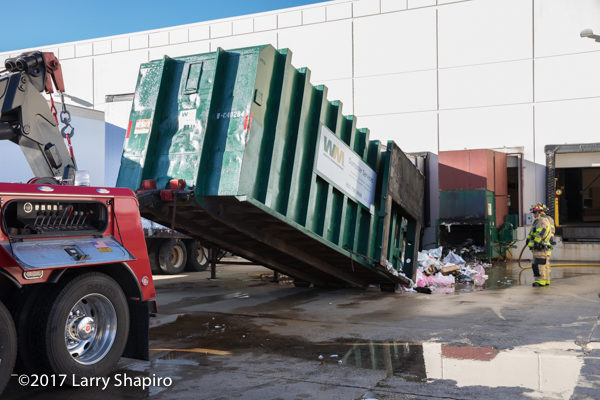 heavy wrecker lifts dumpster