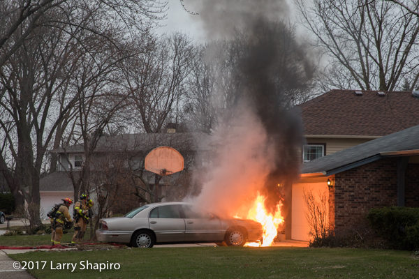 car engulfed in flames near a house