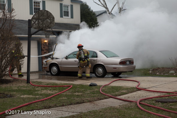 Firefighters extinguish a car fire