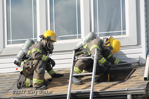firefighter with PPE inspects roof vent hole
