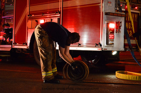 firefighter rolls hose after a fire