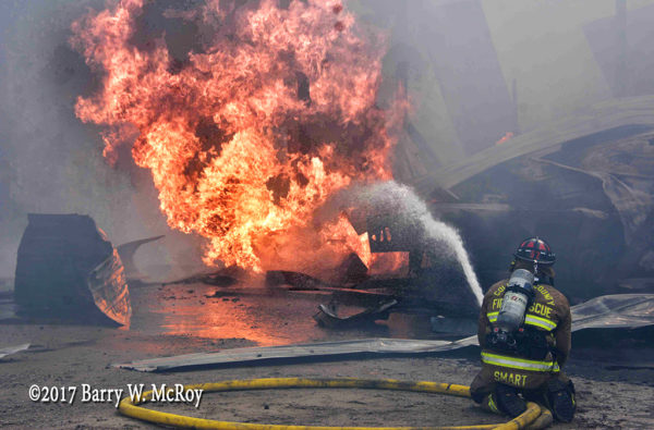 firefighter with hose line and huge flames
