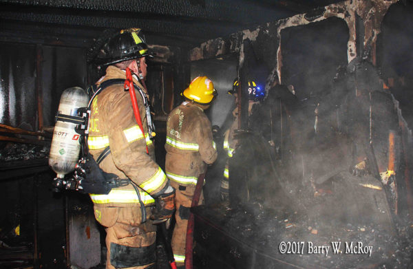 firefighters with hose inside burned out house