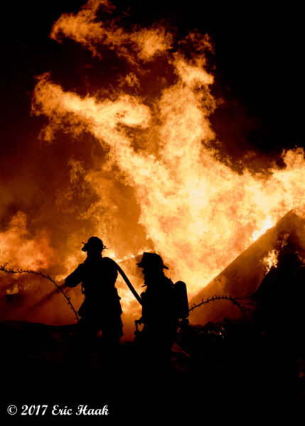 silhouette of firefighters with massive inferno