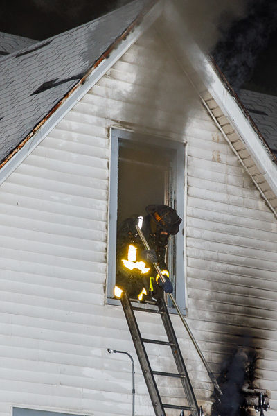 firefighter leans out window with heavy smoke