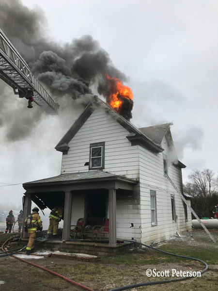 flames burn through roof of a house