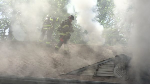 firefighters engulfed in smoke ventilate roof