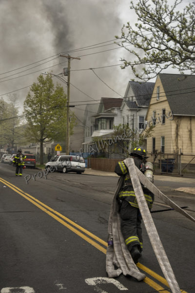 firefighter pulling hose in street