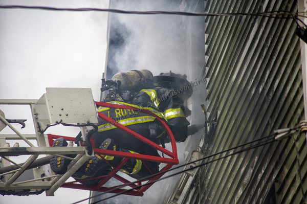 firefighter on aerial ladder tip at fire