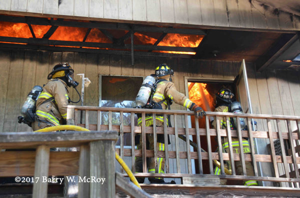 firefighters advance a hose line against heavy fire