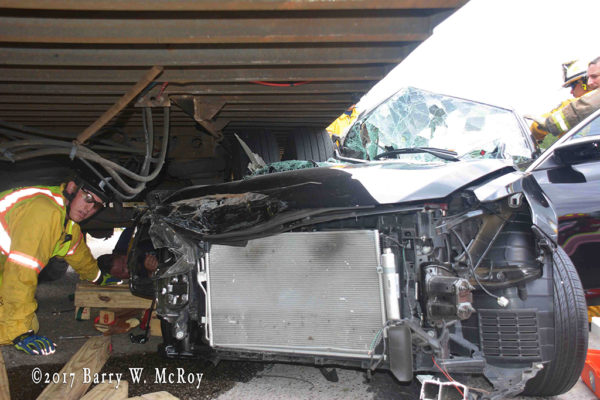 car wedged under semi trailer after crash