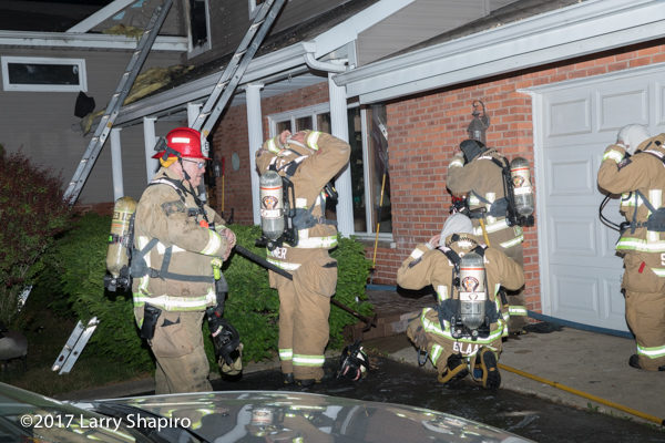 Firefighters prepare PPE before entering house on fire