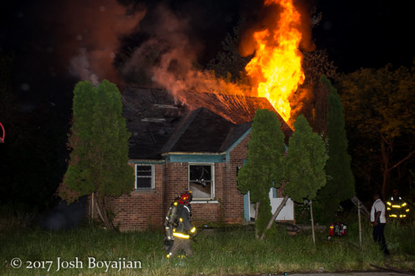 flames through roof of a vacant house