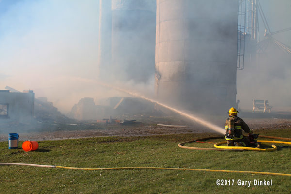 firefighters with hose line at barn fire