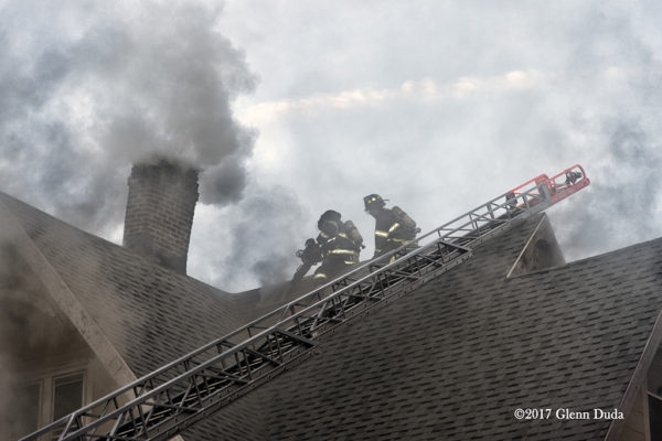 Firefighters vent house roof during a fire