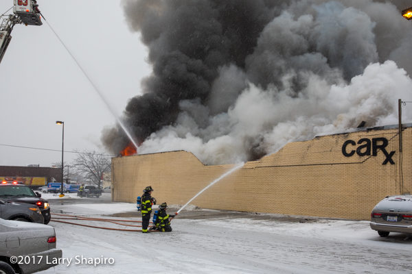 massive smoke and flames from commercial building fire with wall collapse