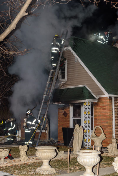 Firefighters ladder a house on fire