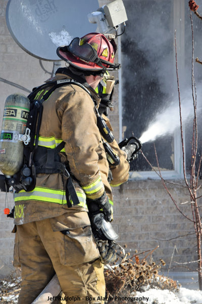 Firefighters operate a hose line during a house fire