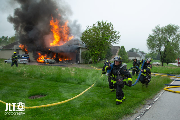 Firefighters with hose line at house fire