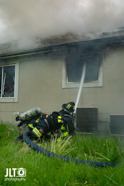 Firefighters with hose line at house fire