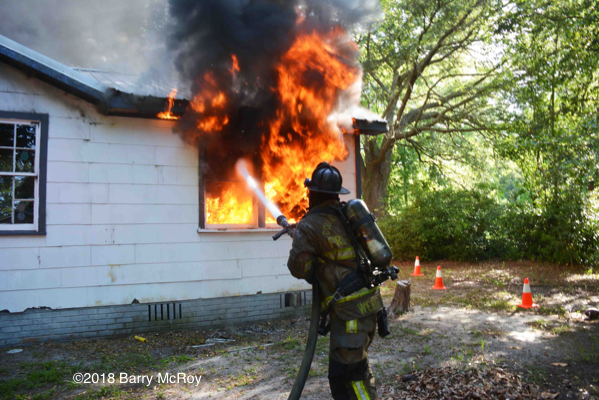Firefighter with hose battles flames