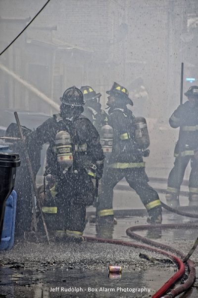Firefighters with hose line in alley