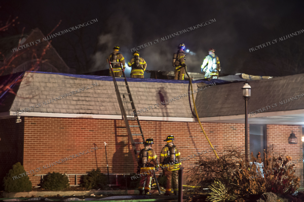 West Haven firefighters extinguish a roof fire at night