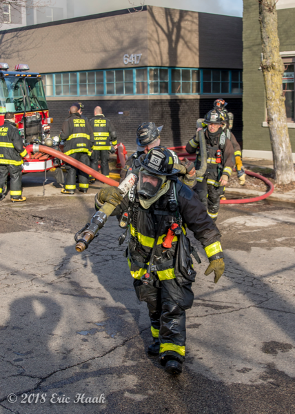 Firefighters dragging a 2 1/2" attack line at a fire scene